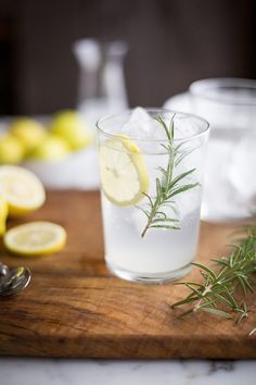 a wooden cutting board topped with a glass filled with water and lemon slices