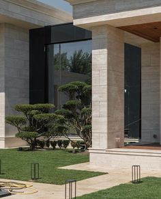 the front entrance to a modern house with trees and grass