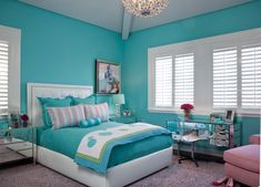 a bedroom with blue walls and white bedding, pink chair, and chandelier