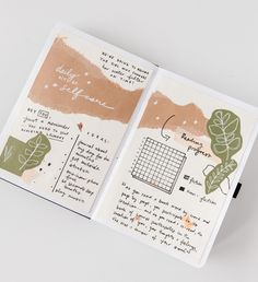 an open notebook with writing on it and some green leafy things in the pages