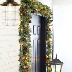 a christmas wreath is hanging on the front door with pine cones and lights around it