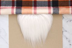 a piece of white hair sitting on top of a table next to a plaid blanket