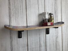 a skateboard mounted to the side of a wooden wall next to two jars filled with condiments