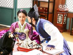 two people dressed in traditional japanese clothing sitting at a table