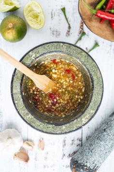 a wooden spoon in a bowl filled with food next to some vegetables and other ingredients