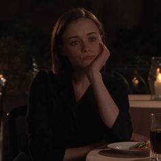 a woman sitting at a table with a plate of food in front of her face