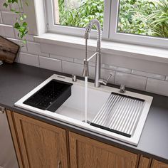 a kitchen sink sitting under a window next to a counter top with a faucet