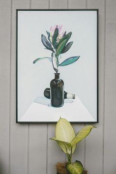 a painting hanging on the wall next to a potted plant