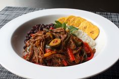 a white bowl filled with meat and rice next to tortilla chips on a table