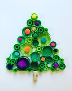 a small christmas tree made out of plastic cups and paper tubes on a white surface