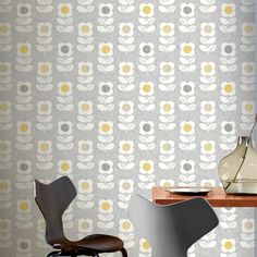 two chairs and a table in front of a wallpapered room with flowers on it