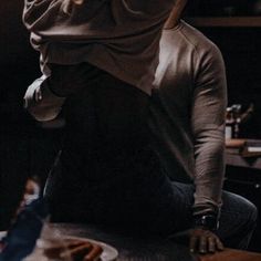 a woman sitting on top of a wooden table holding a cell phone to her ear