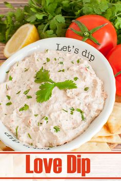 a white bowl filled with dip surrounded by chips, tomatoes and cilantro leaves