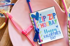 a pink plate topped with two valentine's day cards next to scissors and string