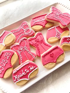 decorated cookies in the shape of baby shoes and booties on a tray with pink icing