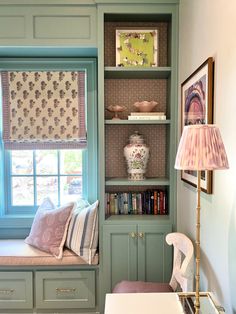 a window seat in the corner of a room next to a book shelf with books on it