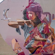 a painting on the side of a building that has birds flying around it and a woman holding a baseball bat