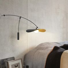 a bed room with a neatly made bed and a lamp on the wall next to it