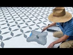 a man in a straw hat is painting a tile floor