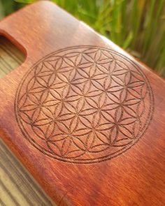 a wooden cutting board with an intricate flower of life design on it's side