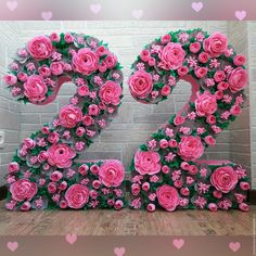 the number twenty two made out of pink roses is displayed in front of a brick wall