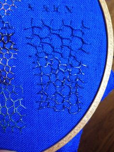 a close up of a blue cloth with some stitching on it and a wooden hoop