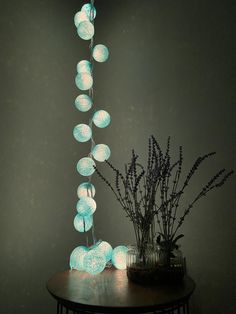 a table topped with a vase filled with flowers next to a string of lights hanging from the ceiling