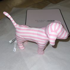 a pink and white striped dog figurine sitting on top of a table next to a laptop computer