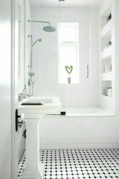 a white bathroom with black and white floor tiles