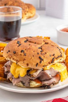 a roast beef sandwich with pineapples and mustard on a white plate next to a cup of tea