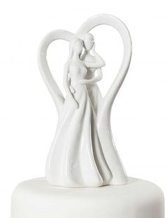 a white wedding cake topper with a bride and groom figurine on it