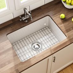 a kitchen sink sitting on top of a counter next to some apples and lemons