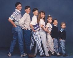 a group of children standing next to each other in front of a blue background,