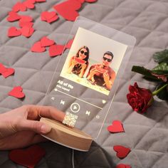 a person is holding a cell phone with a photo on it and some hearts scattered around