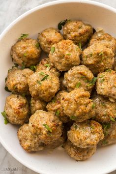 a white bowl filled with meatballs and garnished with parsley on top