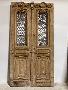 an old pair of wooden doors sitting on top of a white floor next to a wall