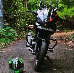 a motorcycle parked on the side of a road next to a green helmet and trees