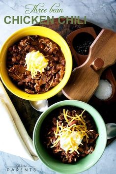 two bowls of chili with cheese on top