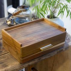 a wooden tray sitting on top of a table next to a potted green plant