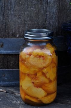 a jar filled with sliced apples sitting on top of a wooden table