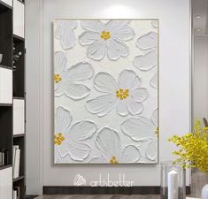 a white and yellow flower painting on a wall in a room with bookshelves