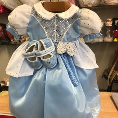 a blue dress and shoes are on display in a toy store's shop window