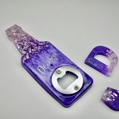 a purple bottle opener and other items on a white surface