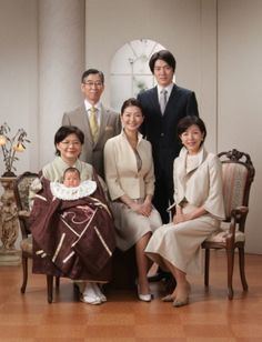 a group of people posing for a photo with a baby in a chair next to them