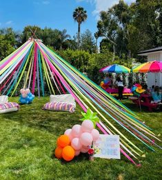 an outdoor party setup with balloons, streamers and decorations on the grass in front of a tent