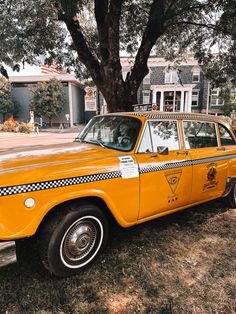 an old yellow taxi cab parked under a tree