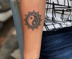 a woman's arm with a tattoo on it that has a yin sign in the middle