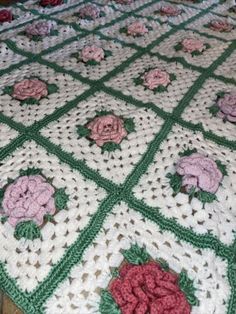 a crocheted blanket with pink flowers on it