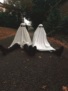 two people dressed in white cloths laying on the ground