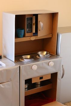 an oven made out of cardboard with bowls and plates in it's opening door